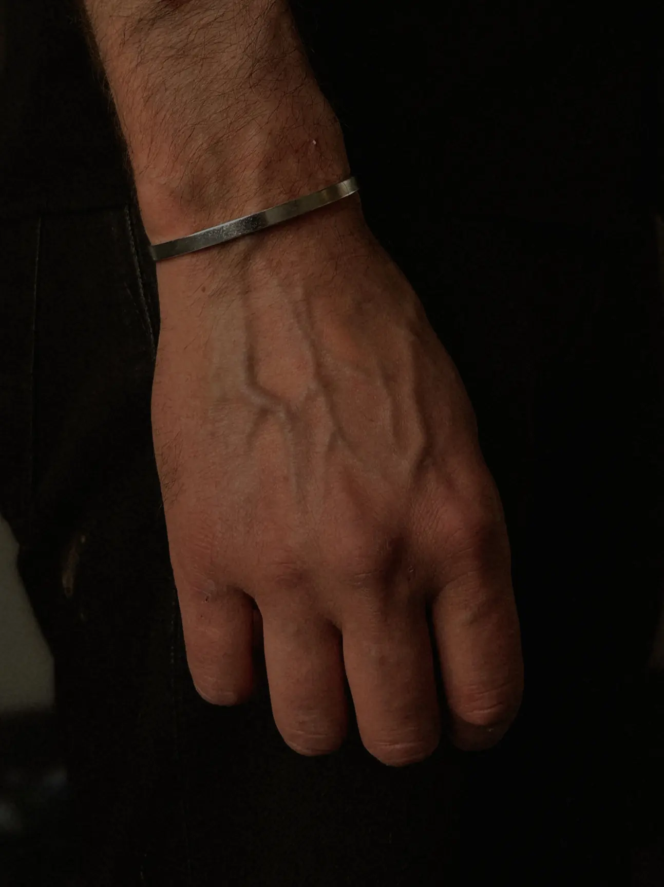 The Refined Arm cuff buren på en handled mot mörka kläder