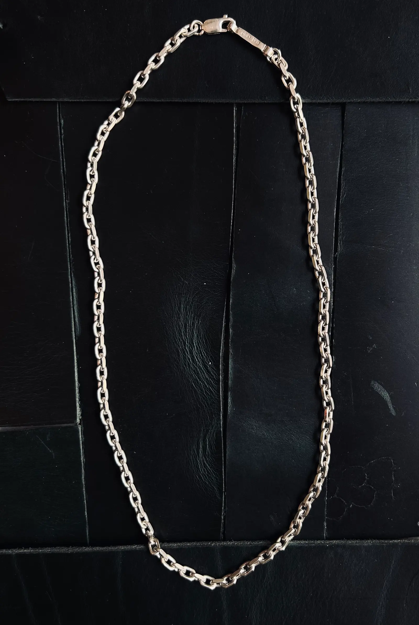 The Bulky Necklace utlagt på svart trä, med BMD-brickan vid låset
