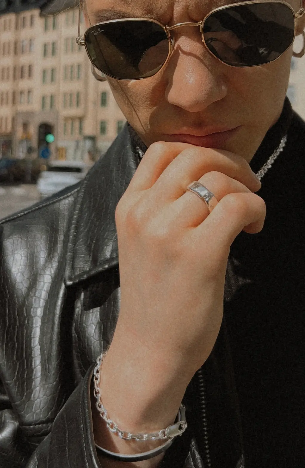 The Sleek Diamond Ring buren på en hand mot hakan, med stadsmiljö i bakgrunden