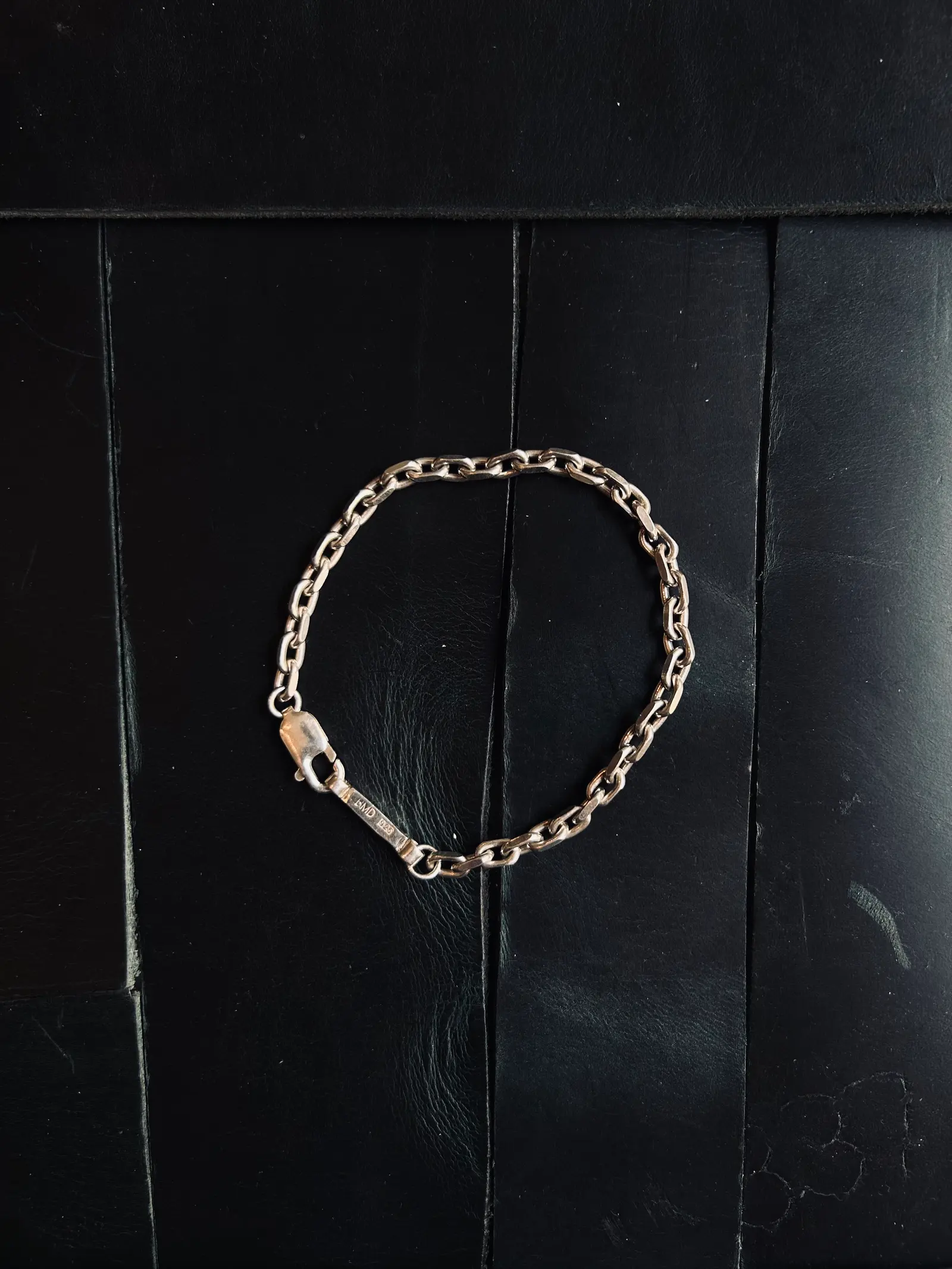 The Bulky Bracelet utlagt i en cirkel på svart trä, med BMD-brickan synlig