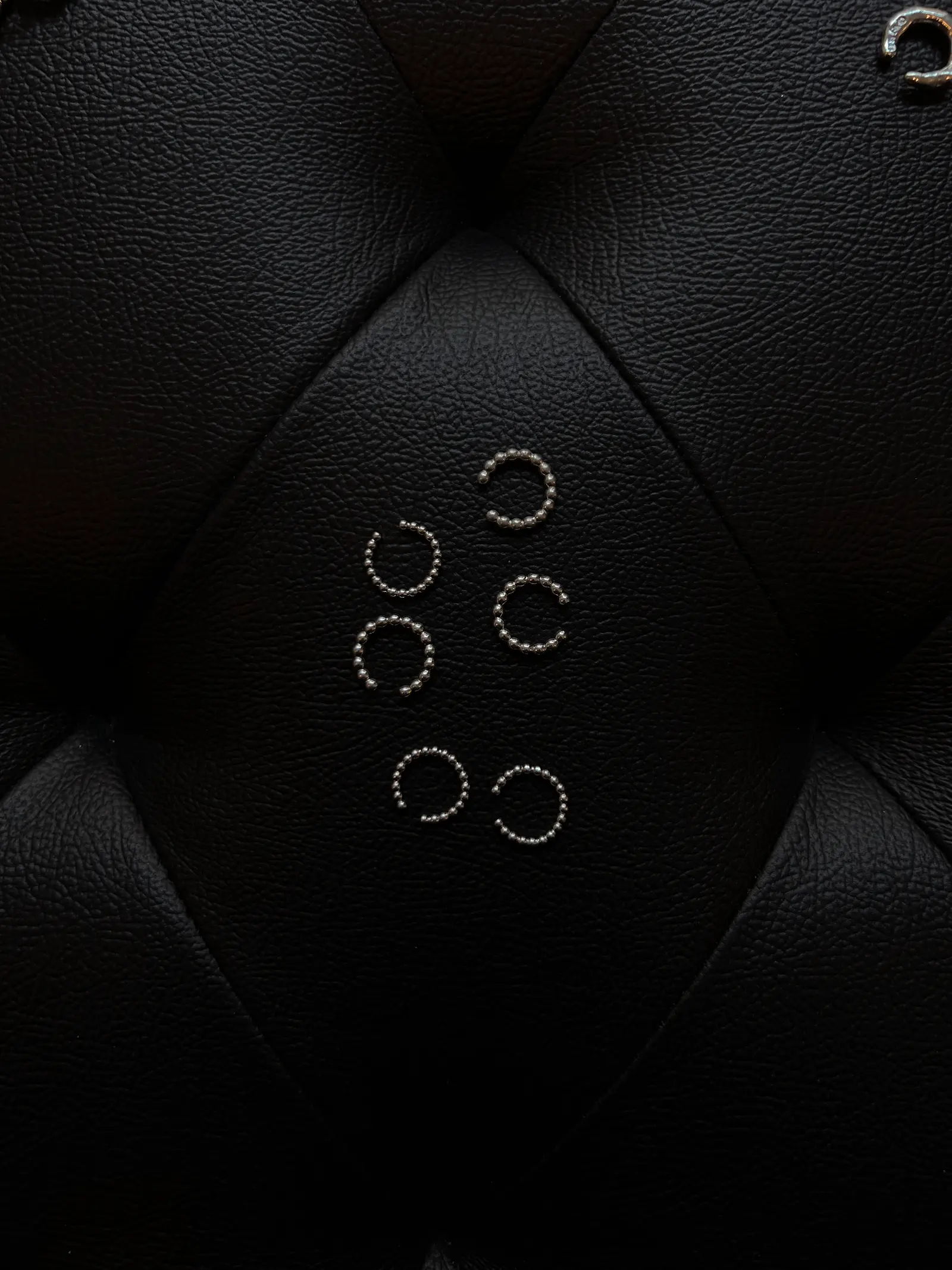Sex Dotty-cuffs i olika storlekar utlagda på svart läder