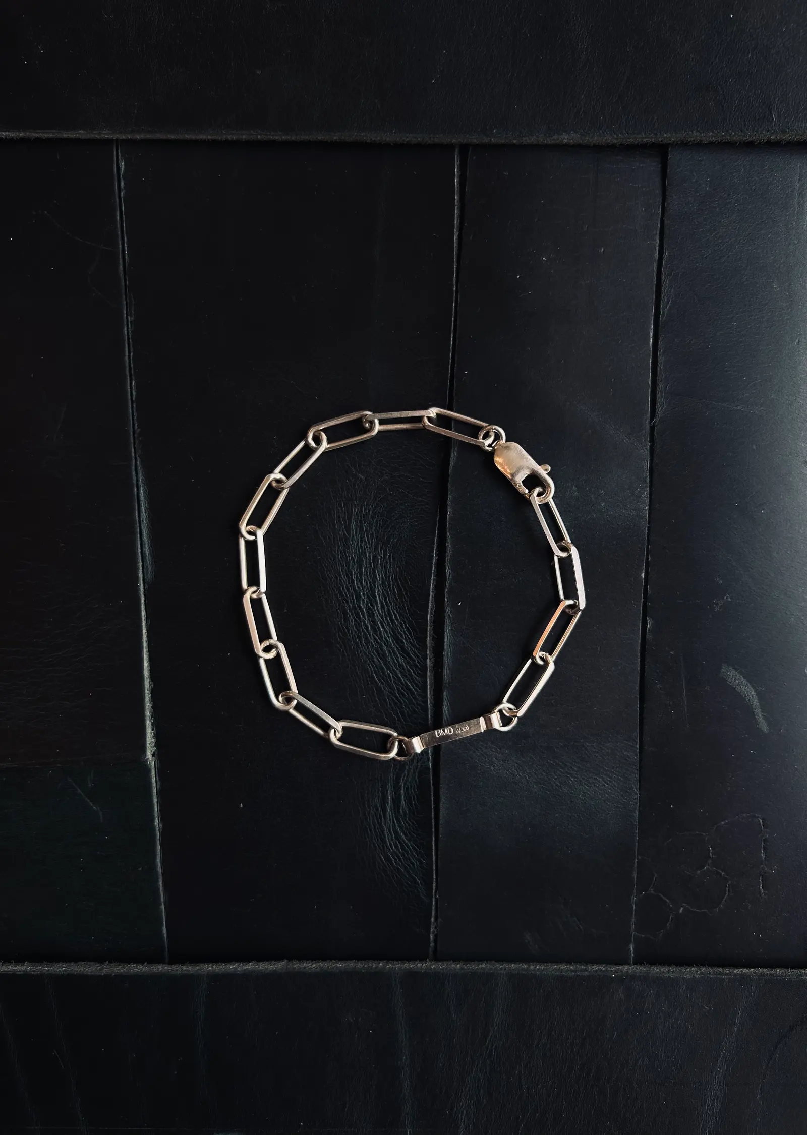 The Given Bracelet utlagt i en cirkel på svart trä, BMD-brickan synlig