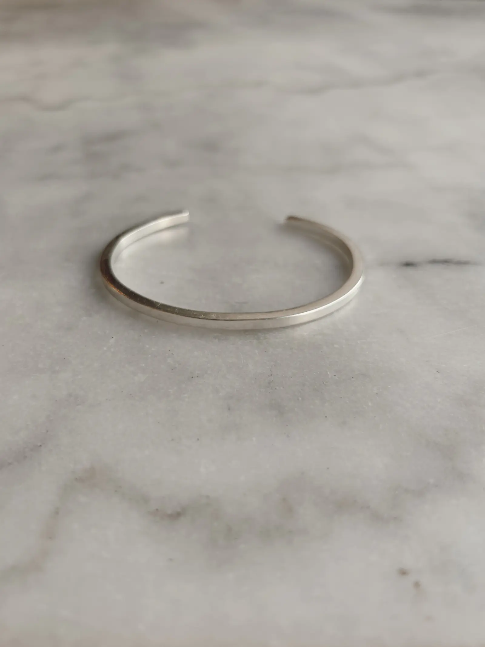 The Tidy Arm cuff på vit marmor, smalare än den bredare modellen