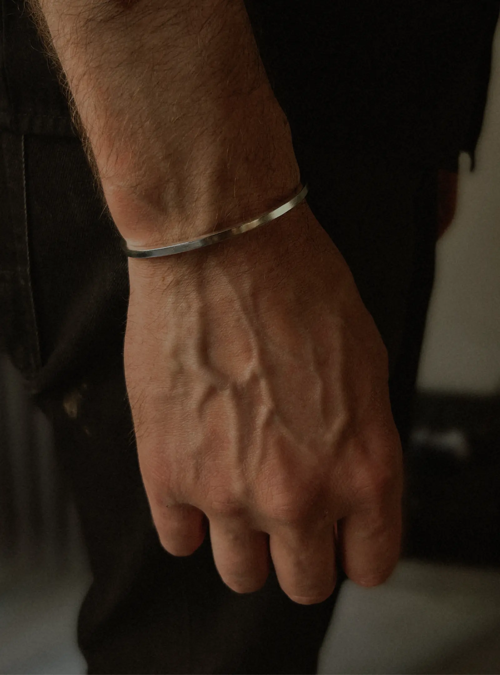 The Tidy Arm cuff buren på en handled mot mörka kläder