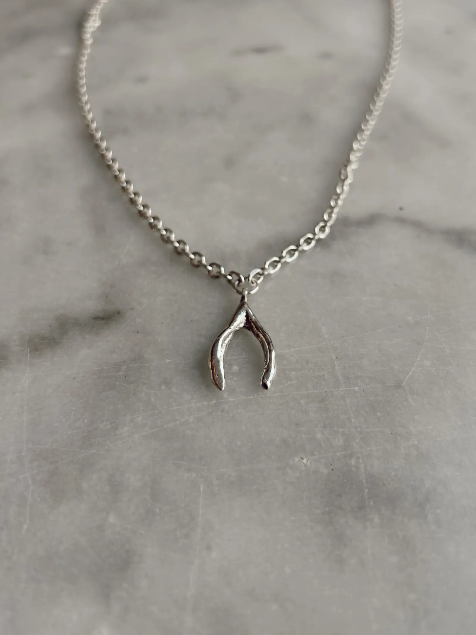 Närbild på önskebenet i polerat silver mot marmor